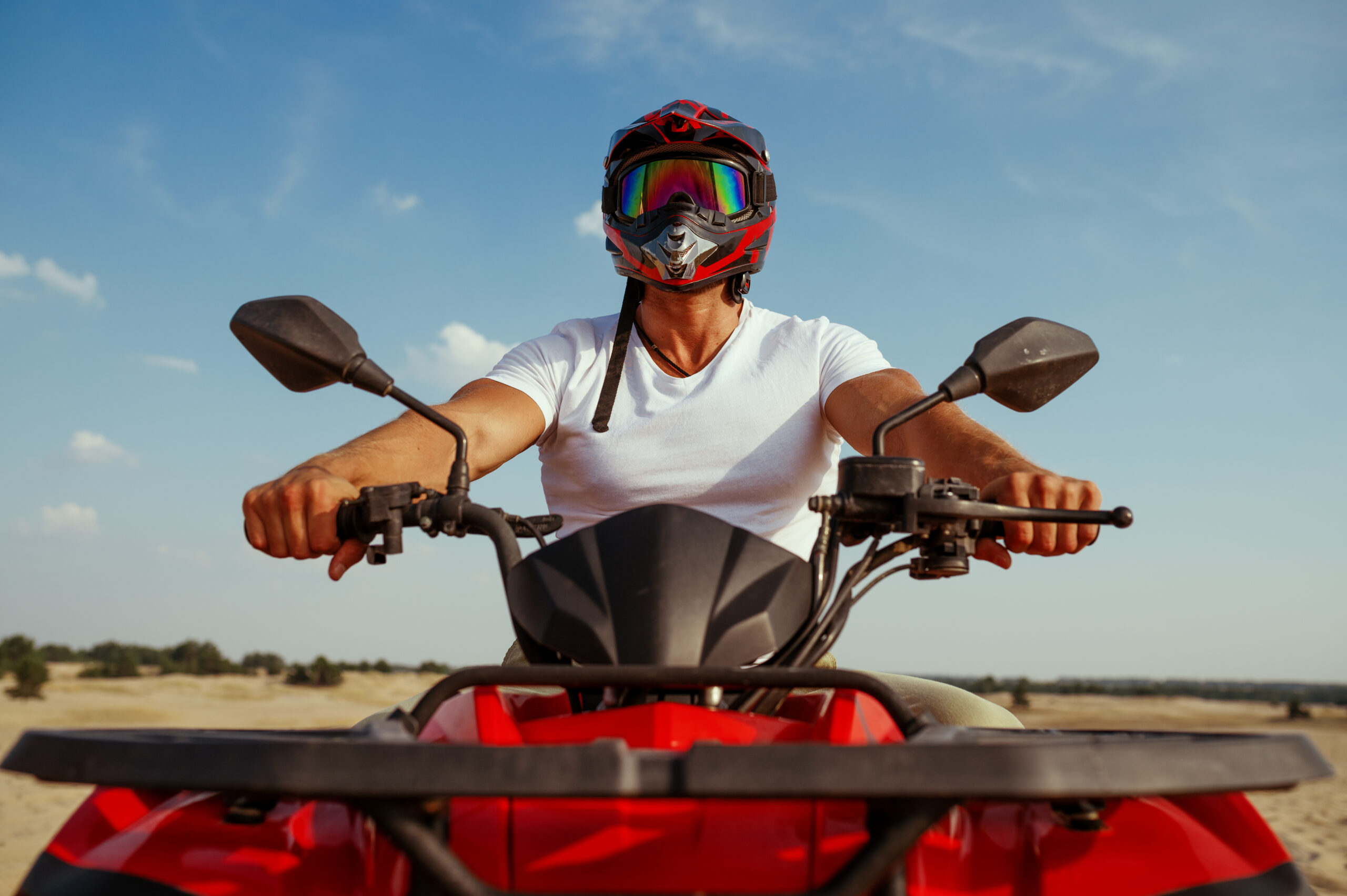 Man in helmet poses on atv in desert, front view. Male person on quad bike, sandy race, dune safari in hot sunny day, 4x4 extreme adventure, quad-biking